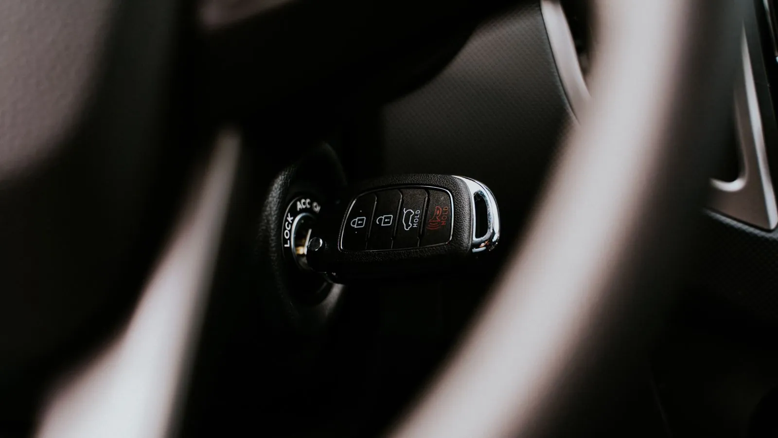 Llave de auto sobre el volante en el interior de un vehículo, en penumbra