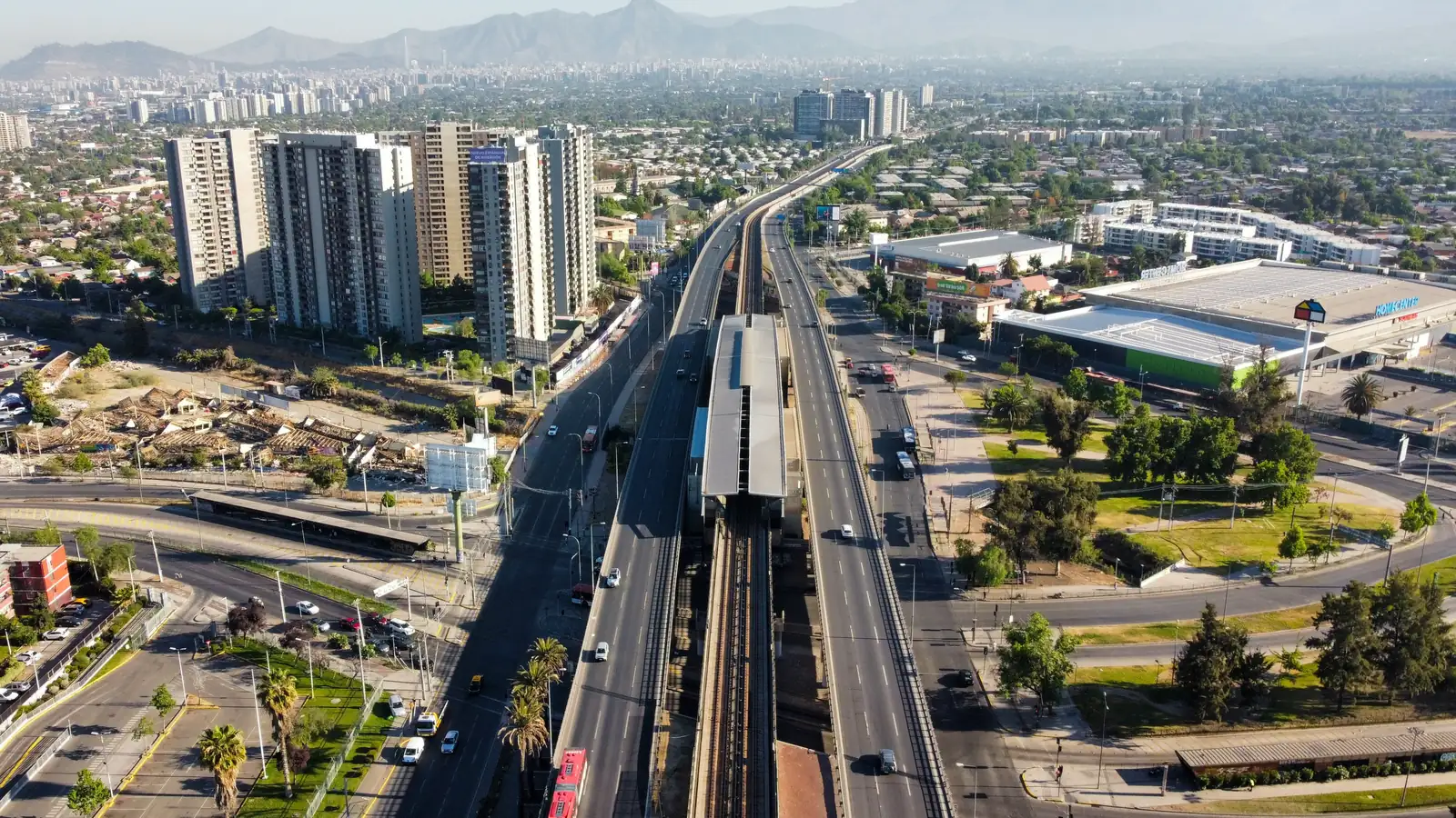 Vista aérea de Santiago con una autopista y la línea de metro cruzando la ciudad hacia la cordillera