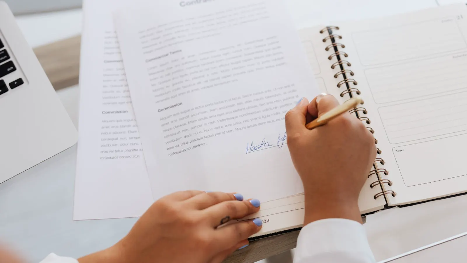 Manos firmando documentación de certificación sobre un escritorio