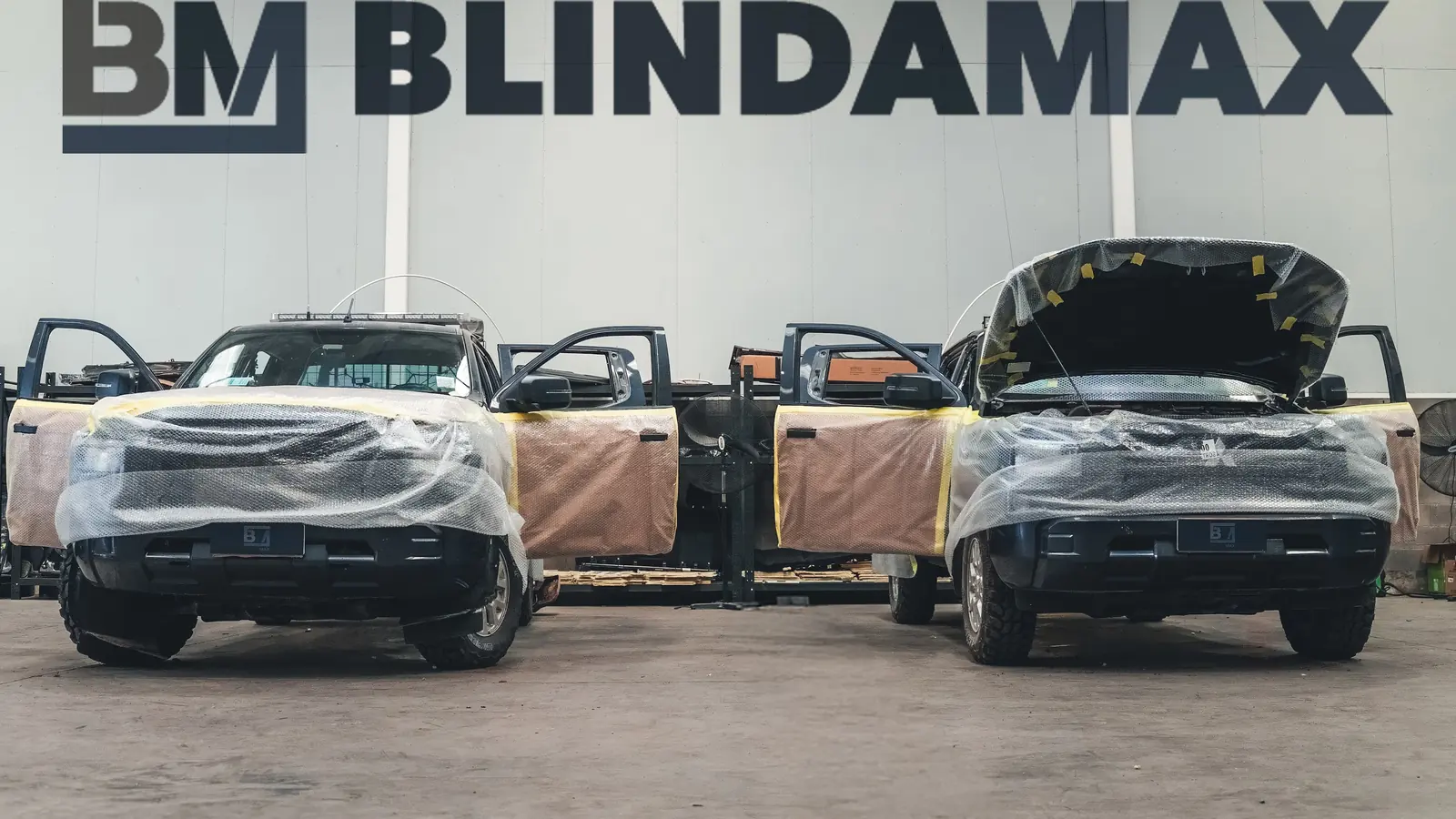 Dos camionetas en pleno proceso de blindaje bajo el logo de Blindamax en la planta de Colina